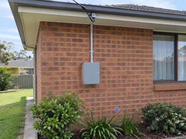 Brick house exterior with new overhead service cable, point-of-attachment bracket and meter box in Tenambit
