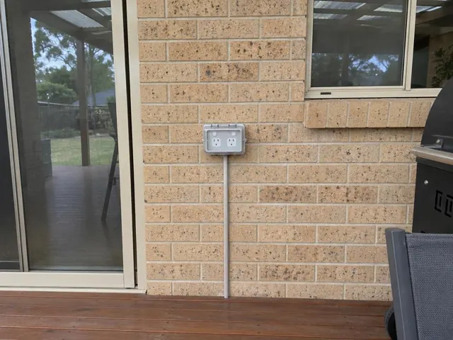 Double outdoor power point on a brick house wall beside a sliding door in Chisholm